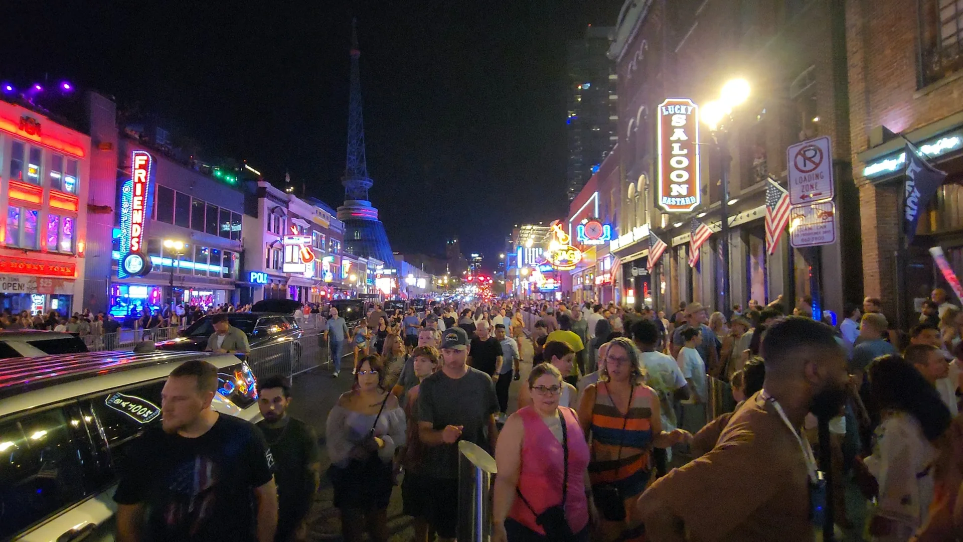 A crowded Lower Broadway illuminated at night.