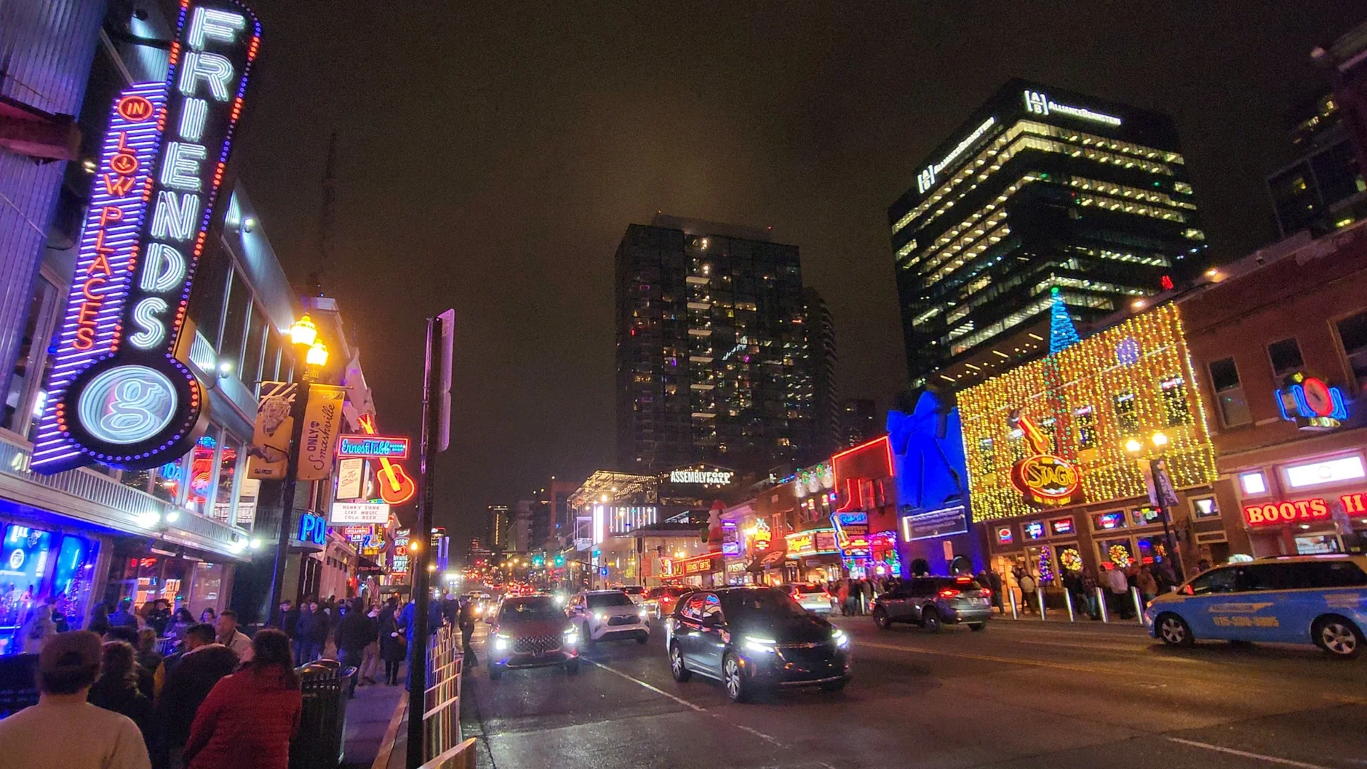 Lower Broadway illuminated by neon signs at night.