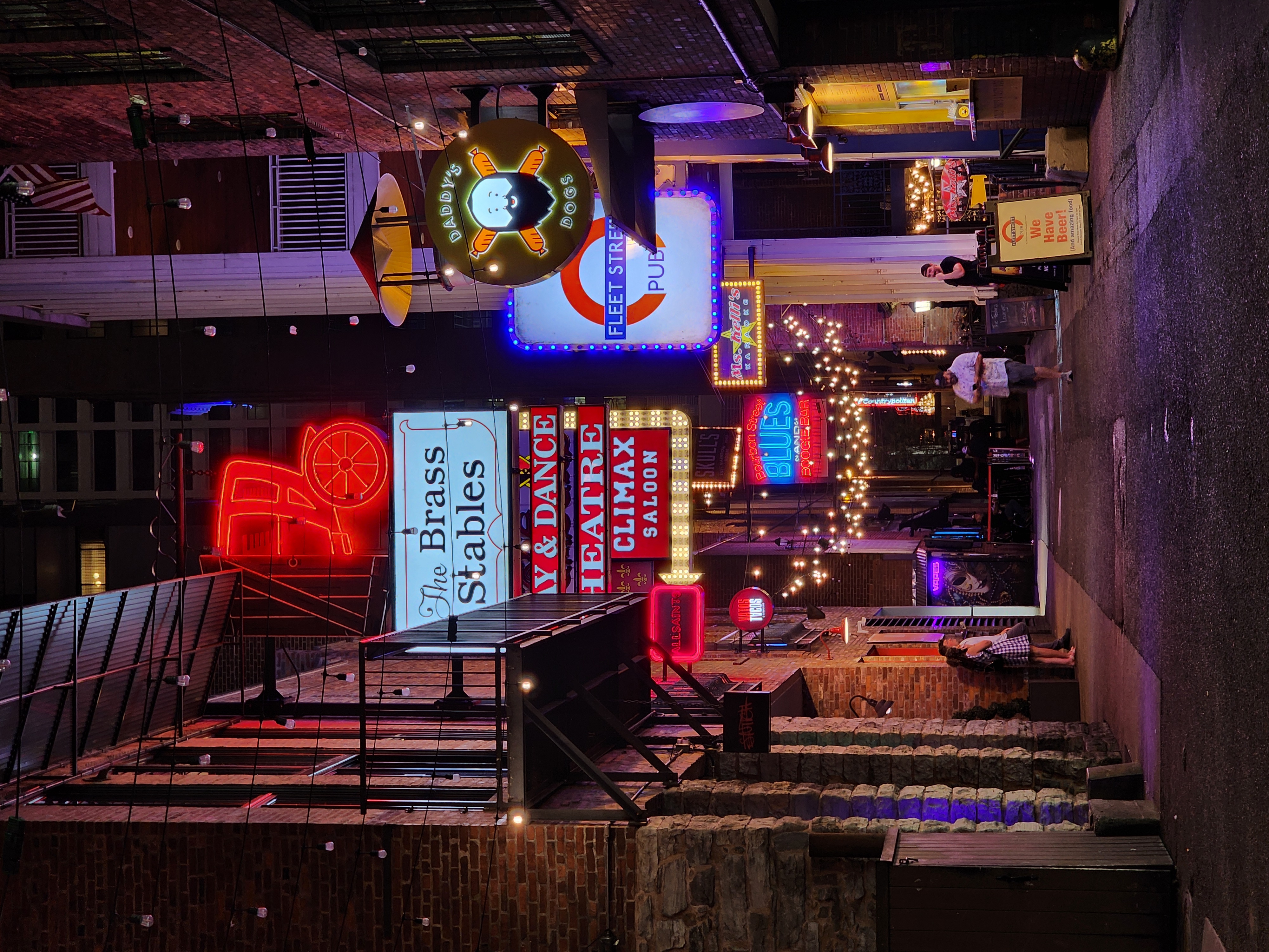 Neon signs and venue entrances along Printer's Alley at night.